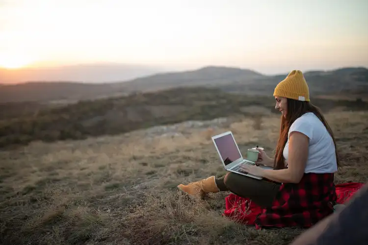 Mulher trabalhando com computador em meio à natureza