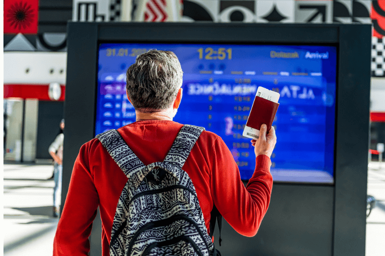 Homem segurando seu passaporte com passagem em aeroporto