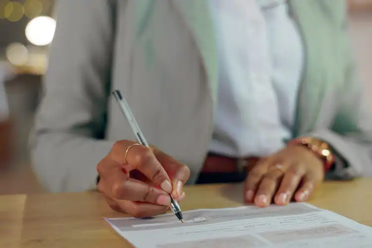 Mãos femininas assinando contrato de trabalho