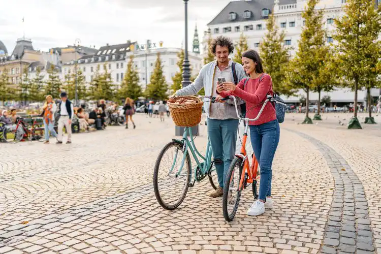 Mulher usando o celular ao lado da bicicleta em uma rua na Dinamarca. 