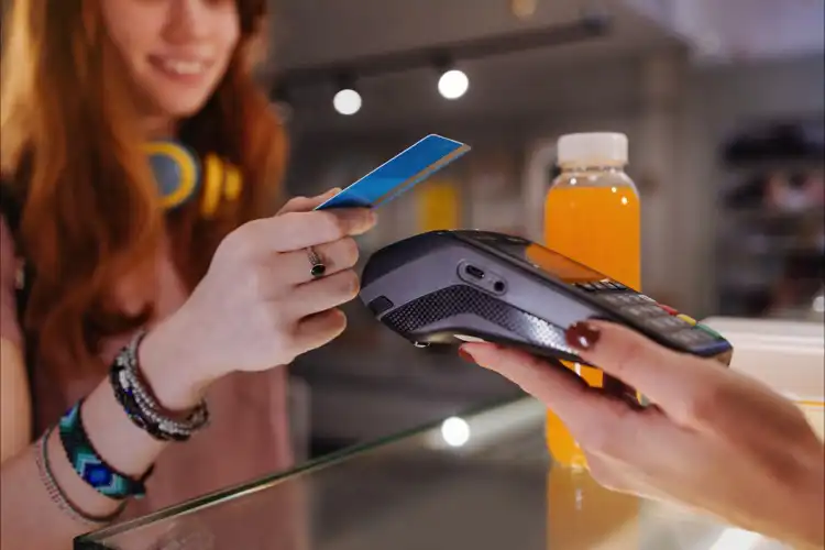 Mulher paga com cartão de crédito por aproximação.