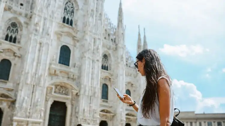 Jovem mulher usando celular em Milão