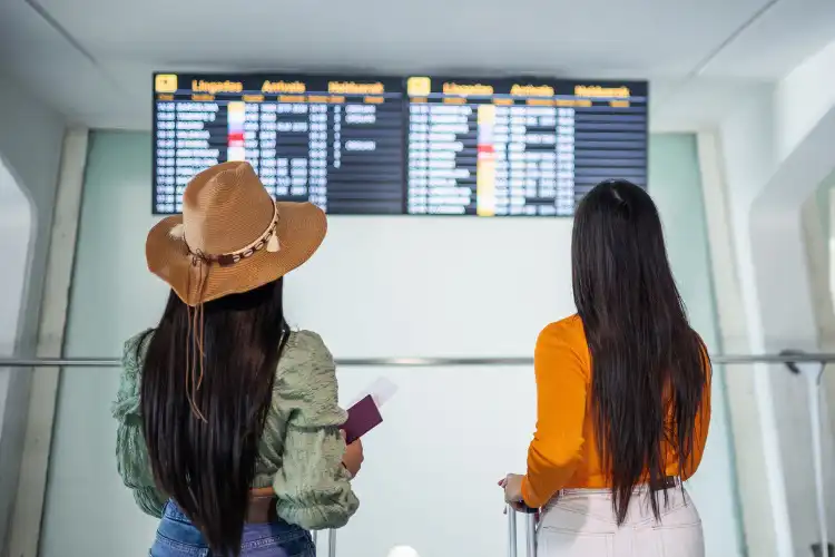 Duas mulheres olhando o painel de embarque no aeroporto.