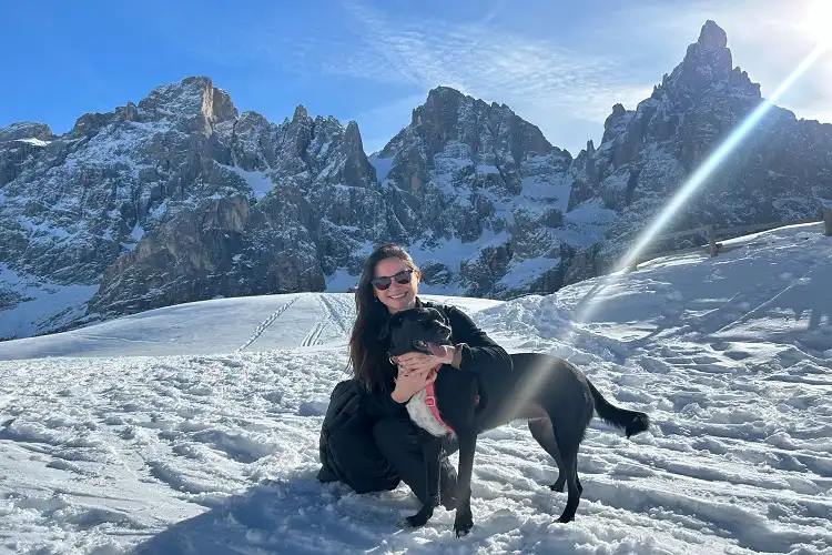 Mulher com cachorro em dia ensolarado na montanha nevada