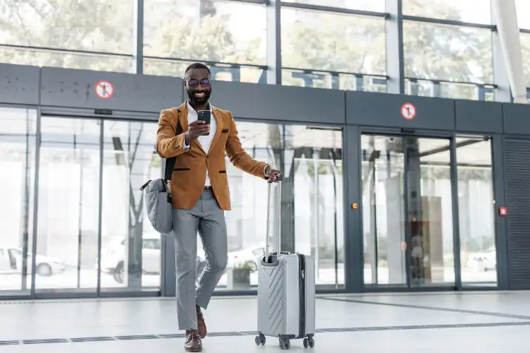 Homem acessando a internet pelo celular enquanto caminha no aeroporto.