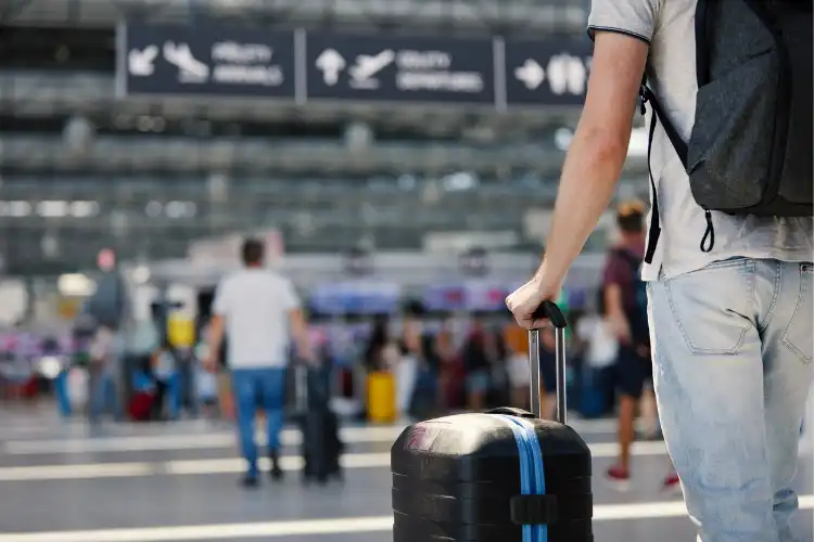 Viajante segurando a mala no aeroporto.