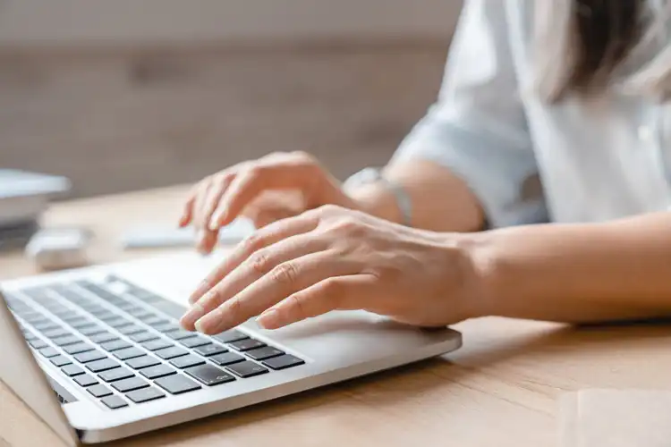 Pessoa usando laptop para calcular impostos da declaração de bens no exterior