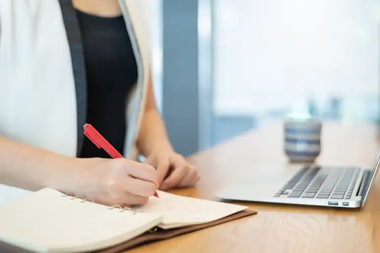 Mulher com laptop e fazendo anotações