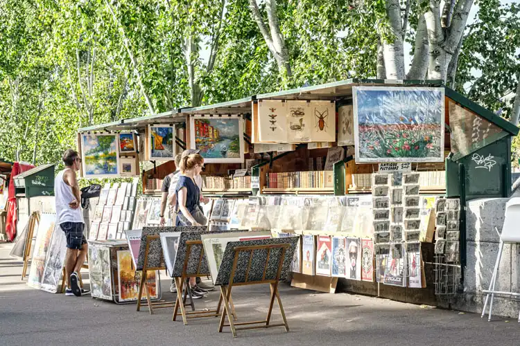 Mulher observa quadros expostos em mercado de rua, na França