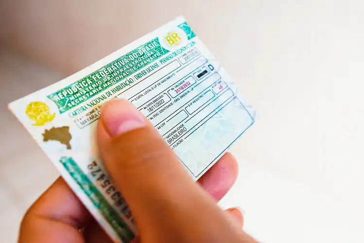 mão segurando carteira de habilitação brasileira (CNH)