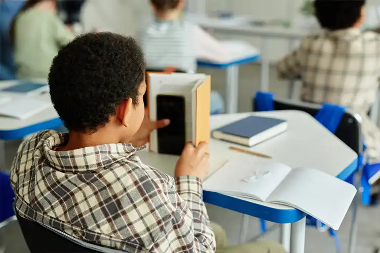 Aluno com celular em aula