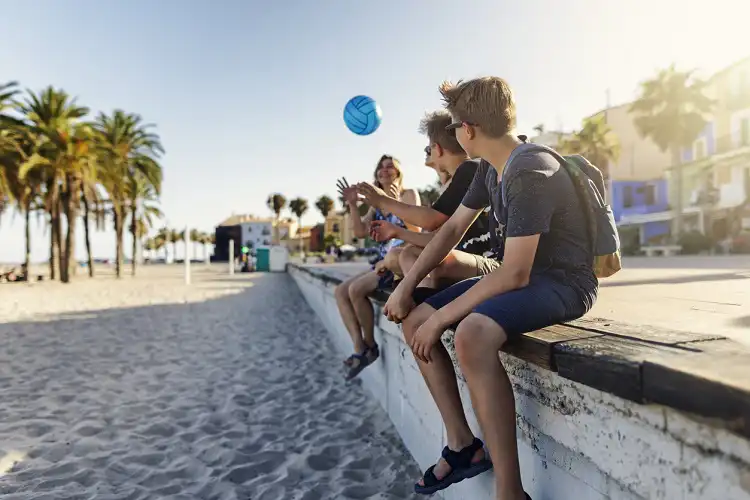 Meninos na praia, brincando de bola, em um dos melhores países da Europa para criar filhos