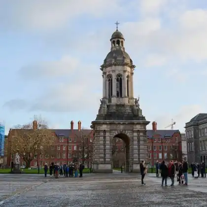 Pátio da faculdade Trinity College, em Dublin, com alunos e turistas passando pelo campus.