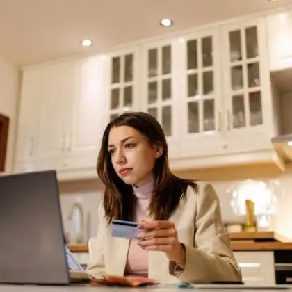 Mulher no computador com cartão de crédito na mão