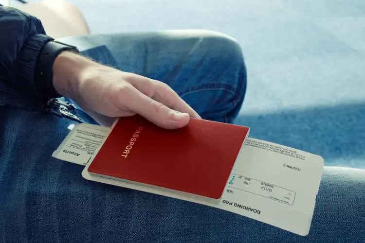 Jovem segurando passaporte e passagens