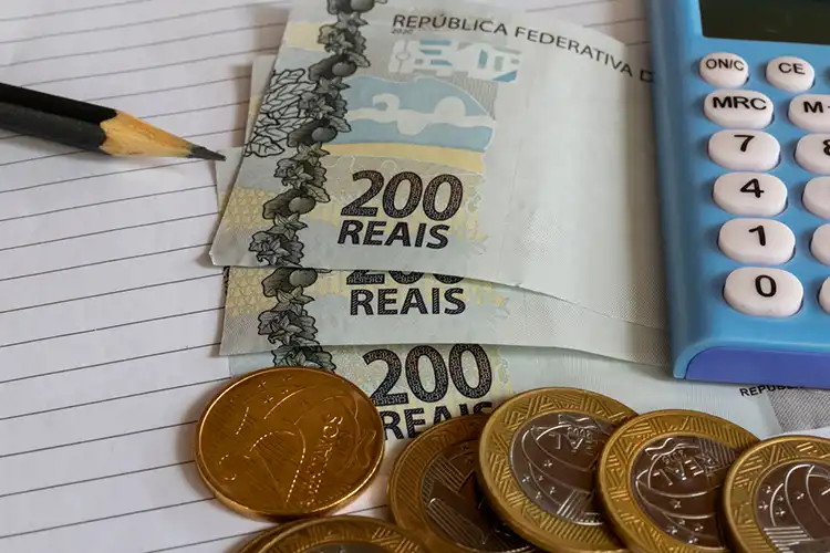 Pessoa calculando a conversão de reais para euros em um caderno