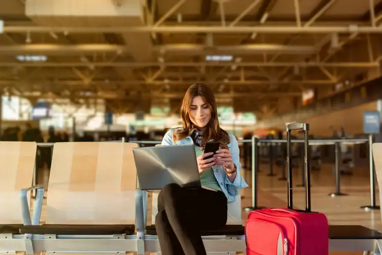 Passageira com smartphone e laptop escolhendo entre Airalo ou America Chip