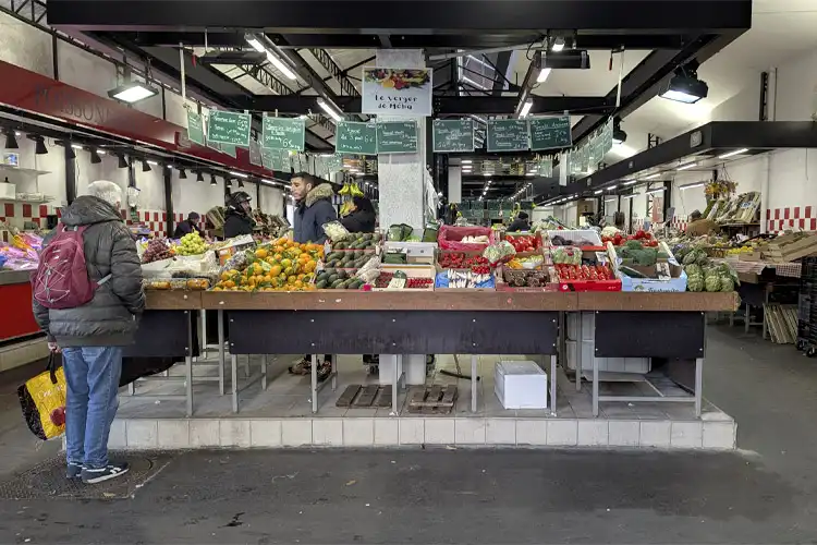 Homem faz compras em mercado municipal em mercado público de pequena cidade, onde custo de vida na França é menor