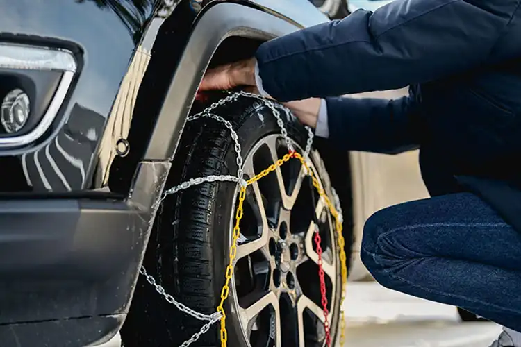 Motorista coloca correntes de neve em pneu do carro