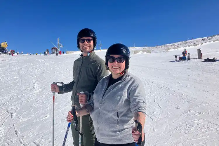 Casal em primeiro plano em dia de sol esquia na Serra da Estrela