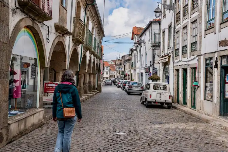 Pessoa caminhando em rua histórica de uma das cidades de Portugal para morar com arquitetura típica.