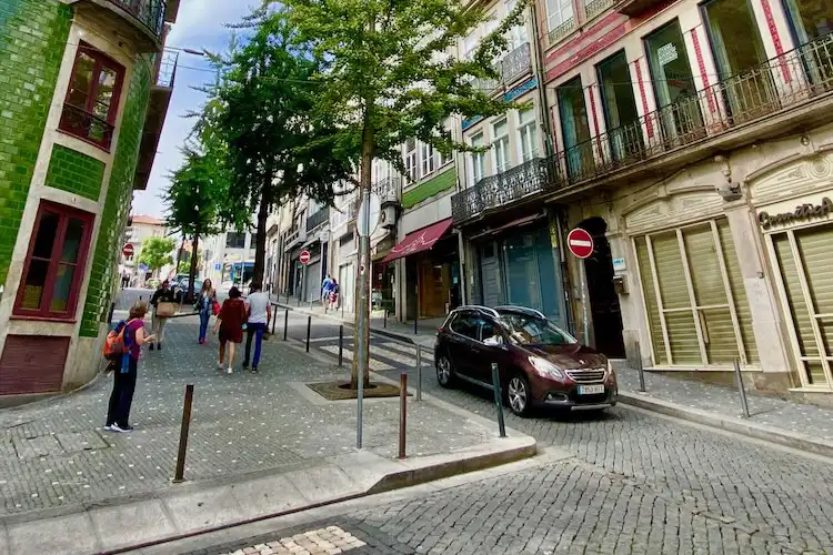 Rua charmosa de uma das cidades de Portugal para morar com prédios coloridos e pessoas caminhando.