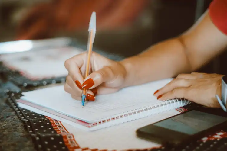 Mulher fazendo anotações no caderno.