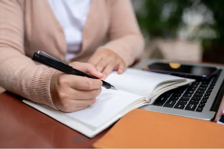 Jovem escrevendo em caderno branco