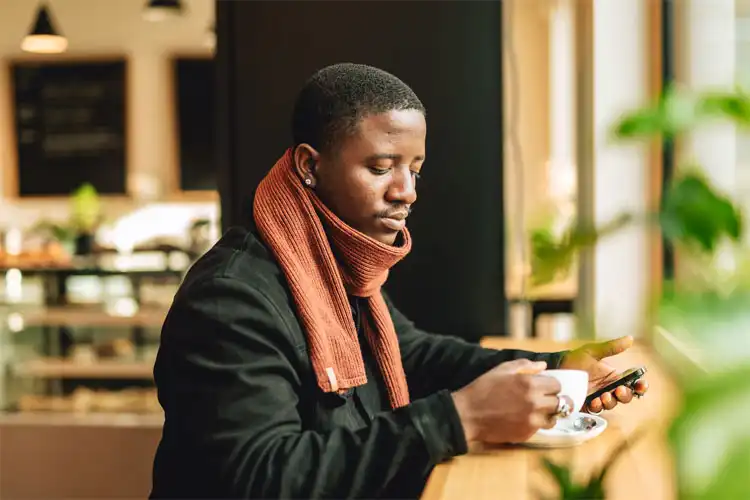 Jovem em um café enquanto opera smartphone