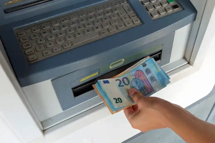 Pessoa retirando notas de euro em caixa eletrônico na Europa