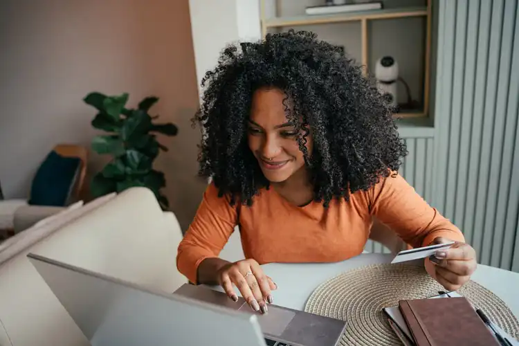 Mulher adulta consulta dados em um computador, podendo ser conta global Nubank ou Wise