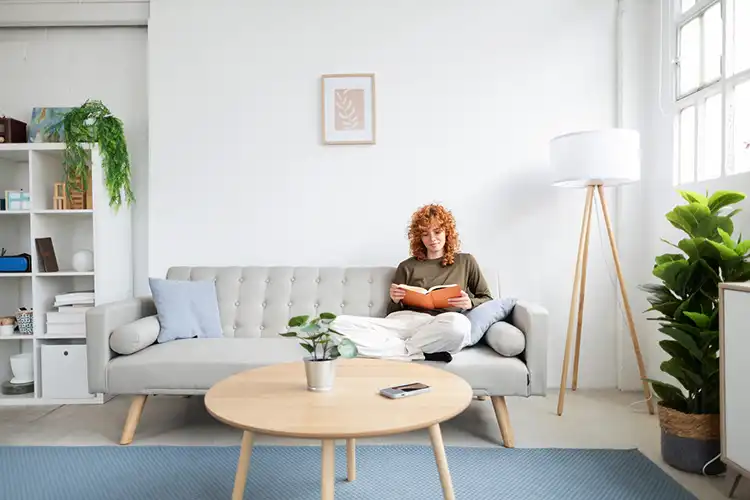 Mulher lê um livro no sofá em seu apartamento em Braga, Portugal