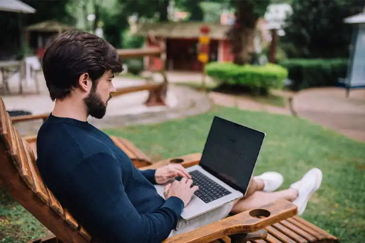 "Nômade digital" utiliza laptop enquanto relaxa em um jaradim externo