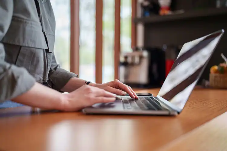 Mulher digita em teclado de laptop