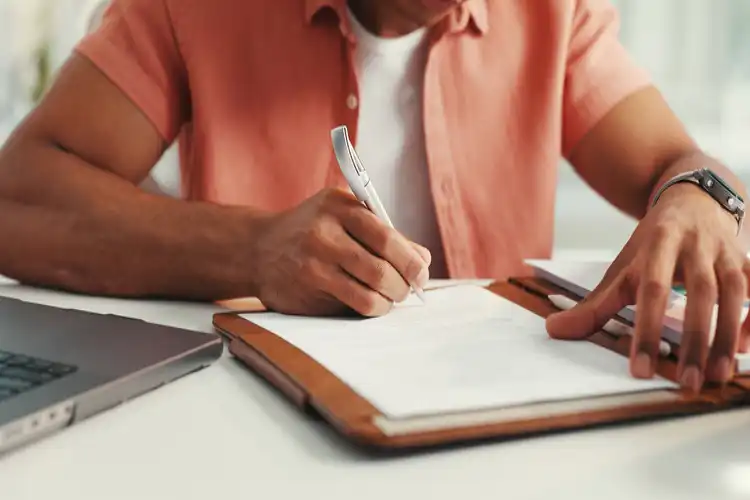 Homem toma notas sentado em uma escrivaninha