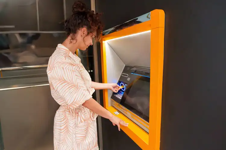 Mulher jovem utilizando um caixa automático depois de abrir uma conta na Espanha