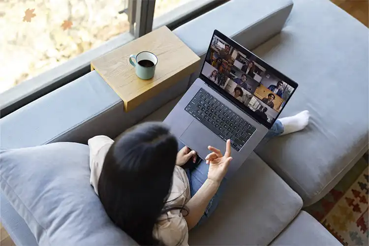 Mulher utiliza computador para aula em grupo com seu laptop