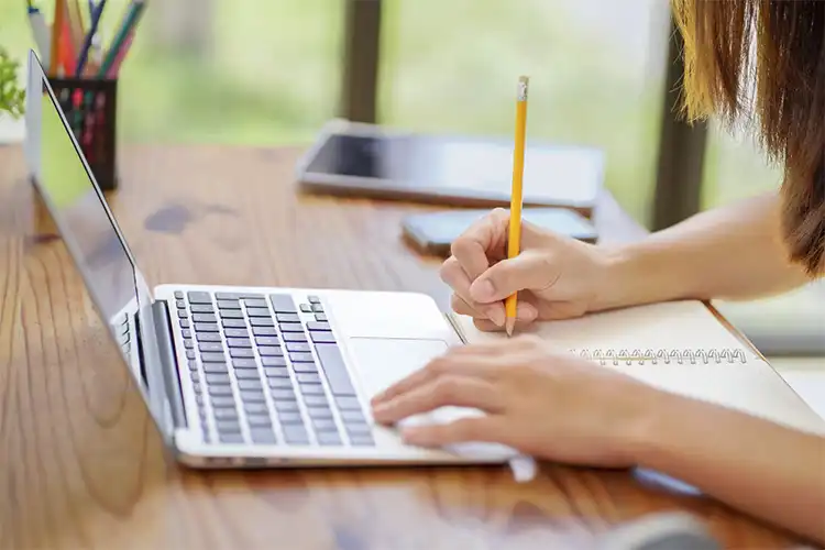 Jovem utiliza computador e caderno para fazer exercícios de Fluencypass ou Open English