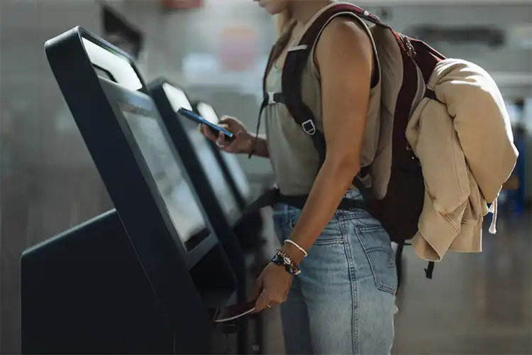 Viajante consulta sua passagem para França em um terminal de autoatendimento