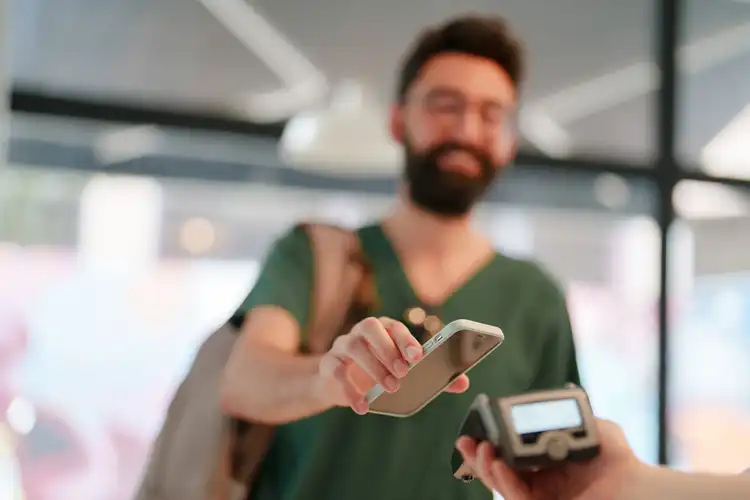 Jovem pagando com o cartão no celular.