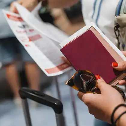 mulher com passaporte e apólice de seguro viagem nas mãos