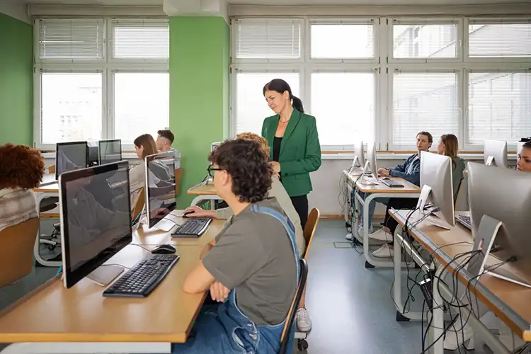 Professora e estudantes durante aula em laboratório de informática