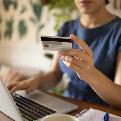 Mulher usando o notebook para fazer pagamentos internacionais com seu cartão de crédito