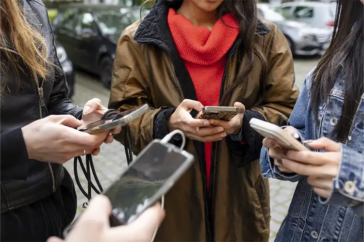 Grupo de jovens utilizando celular para consultar aplicativos
