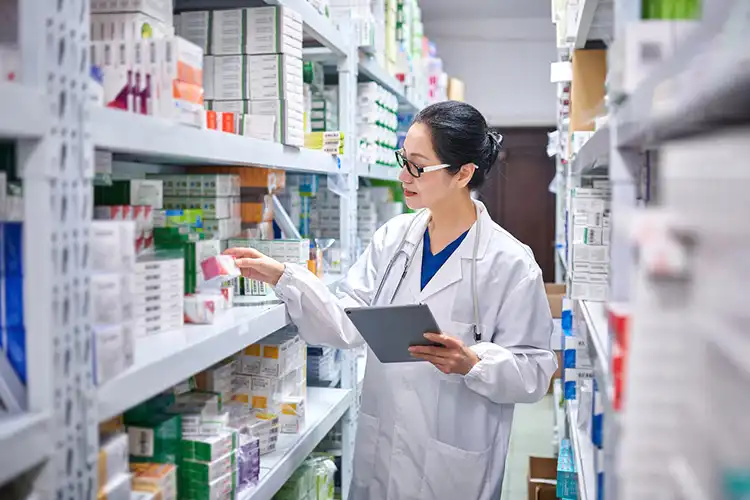 Farmacêutica analisa caixas de medicamentos em farmácia