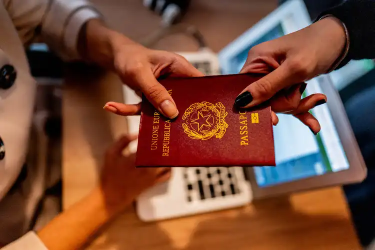Pessoa entrega seu passaporte italiano em recepção.