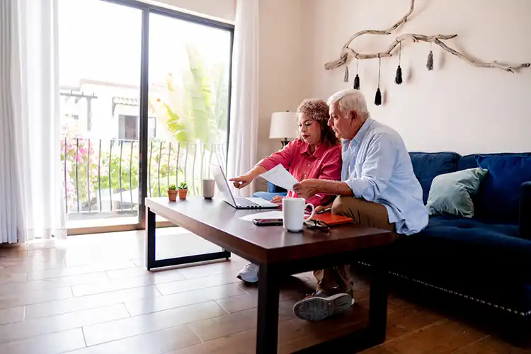 Casal sênior calculando as finanças domésticas na sala de casa