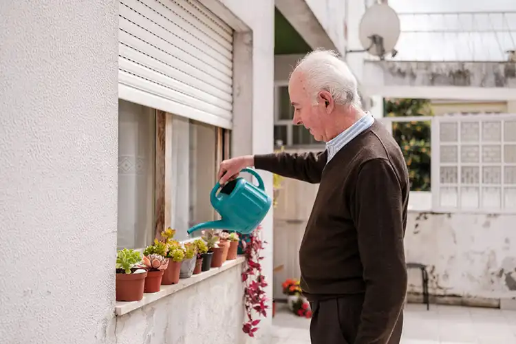 Aposentado rega as plantas da varanda de sua casa em Portugal