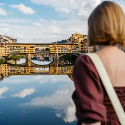 Mulher viaja para Itália e contempla Ponte Vecchio, em Florença.