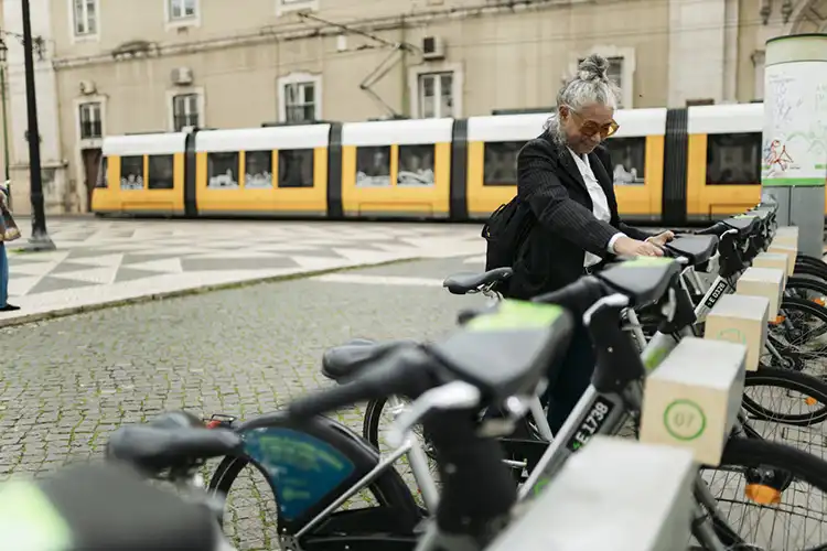 Empresária aposentada alugando uma bicicleta em uma estação de compartilhamento em Lisboa